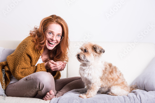 schöme rothaarige Frau erzieht ihren Hund auf der Couch