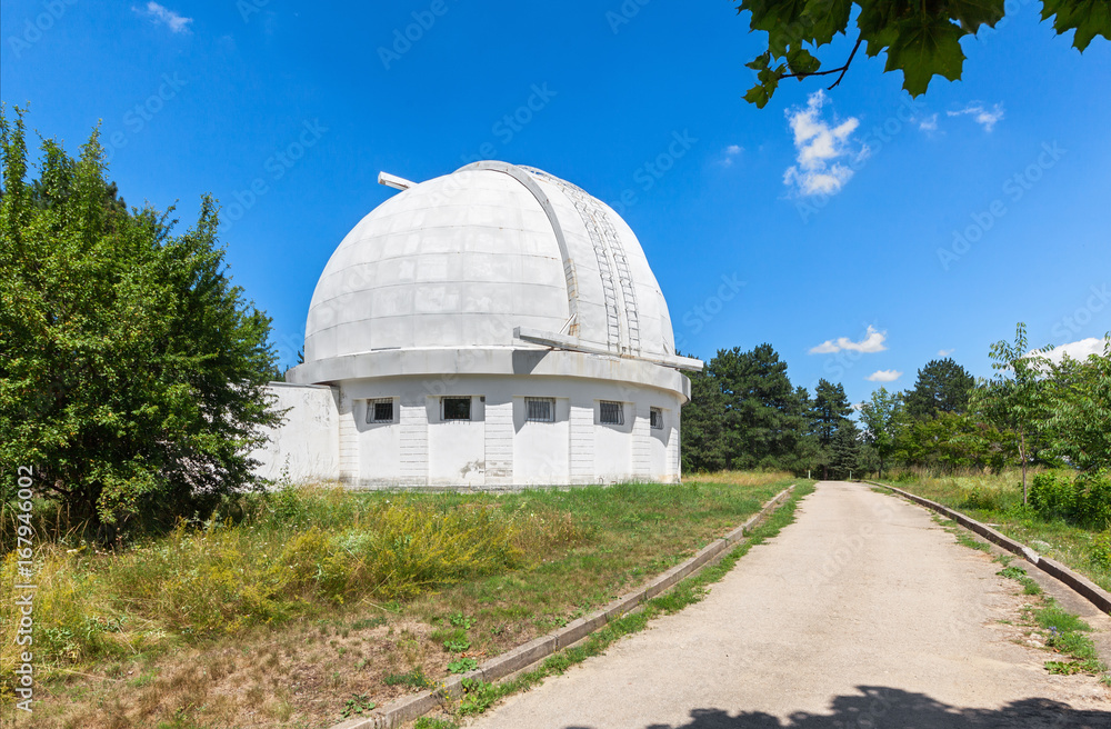 Road next to the Observatory building with a retractable dome for the coronograph. The dome of the telescope during the day. Road next to the Observatory building with a retractable dome for the coronograph. The dome of the telescope during the day.