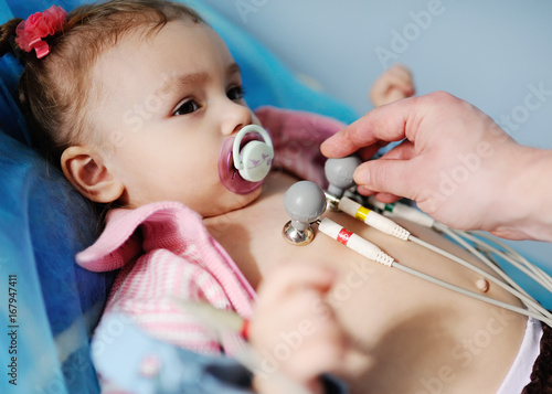 Fotografie baby girl cute doctor makes an electrocardiogram close up.