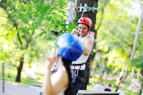 boy and girl climbing on rope road in a special outfit and helmet. The instructor of rock climbing and overcoming obstacles