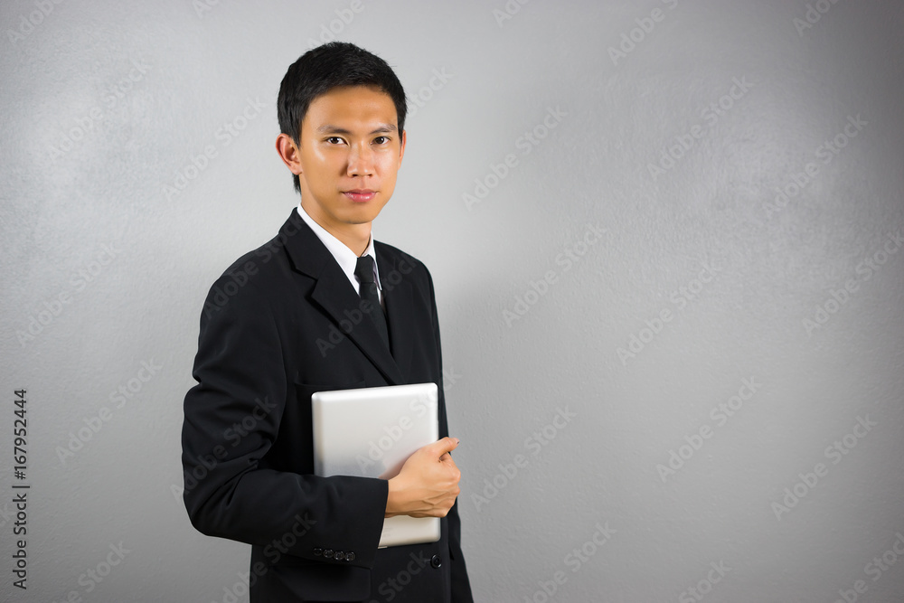 business, people, gesture and technology concept - smiling Asian businessman with tablet pc computer over gray concrete wall background business, people, gesture and technology concept - smiling Asian businessman with tablet pc computer over gray concrete wall background