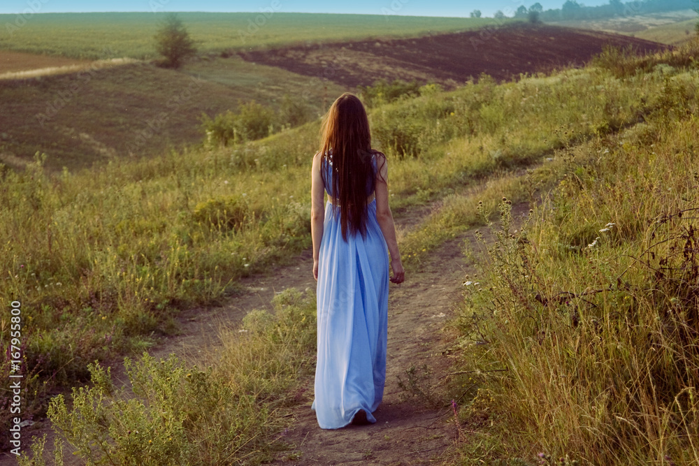 Brunette walking on the road at sunset in the evening Brunette walking on the road at sunset in the evening