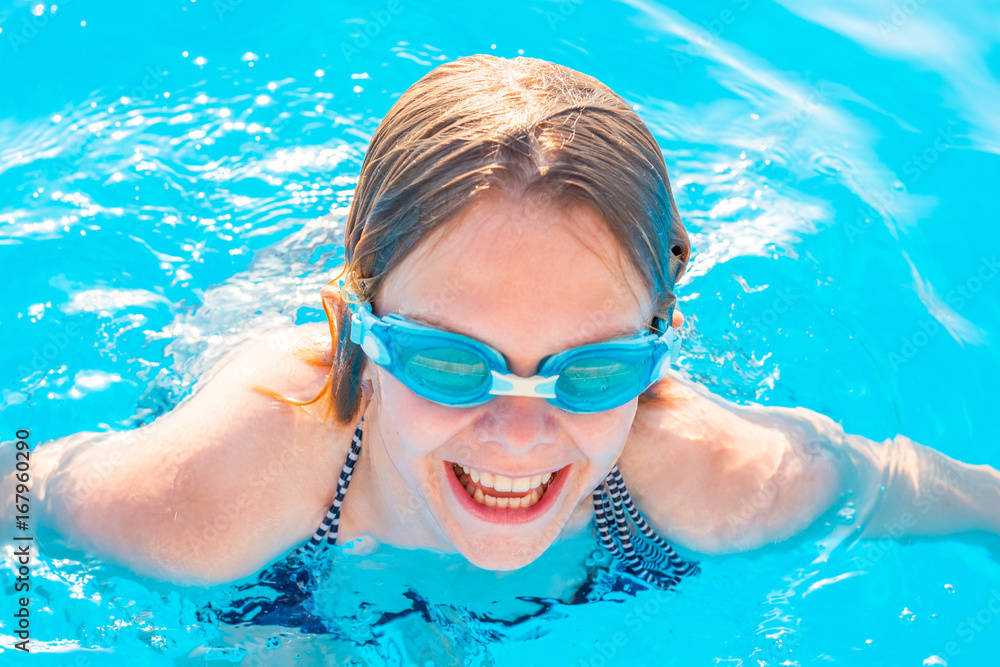 Naklejka premium Girl swims in the pool with glasses for swimming