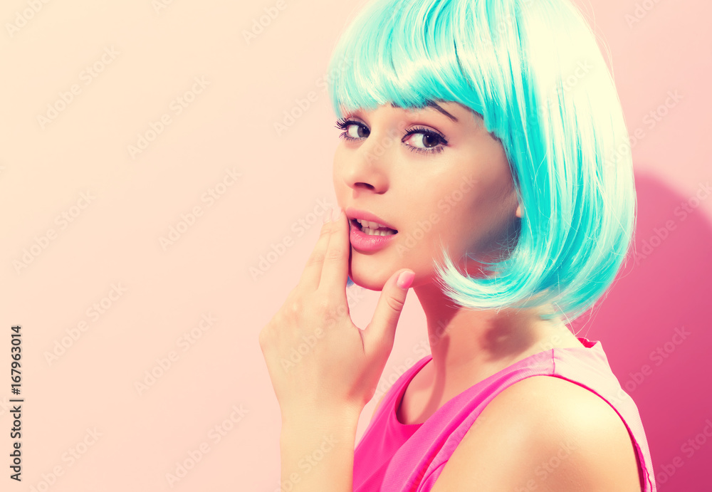 Beautiful woman in makeup with a bright blue wig on a pink background Beautiful woman in makeup with a bright blue wig on a pink background