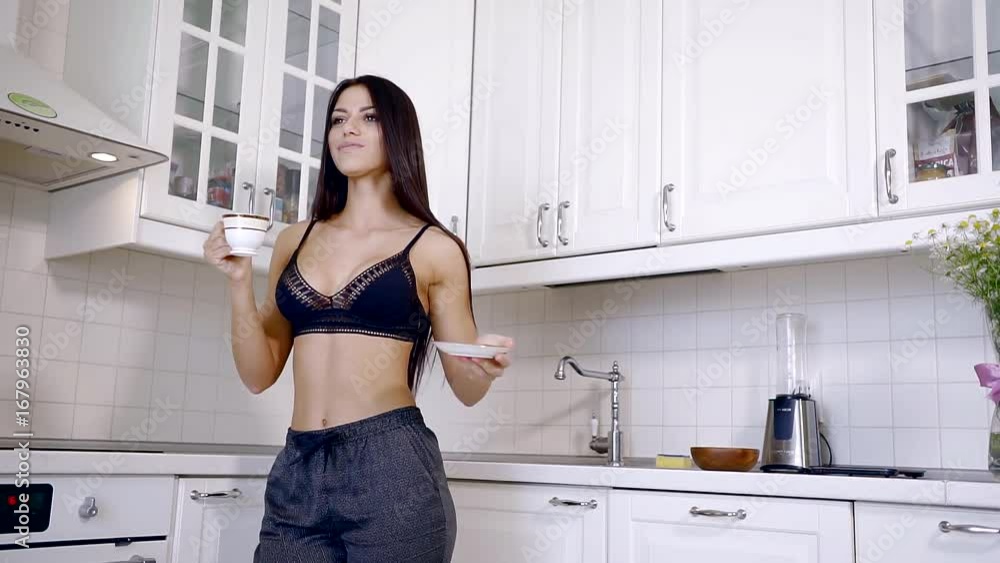 Happy young woman dancing in the kitchen in my pajamas in the morning to listen to music and coffee house Happy young woman dancing in the kitchen in my pajamas in the morning to listen to music and coffee house