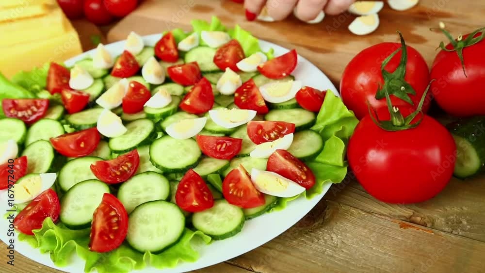 Preparation of homemade vegetable salad with cherry tomatoes, cheese and quail eggs. Female hands are cut with a knife of olives. Camera moves from right to left Preparation of homemade vegetable salad with cherry tomatoes, cheese and quail eggs. Female hands are cut with a knife of olives. Camera moves from right to left