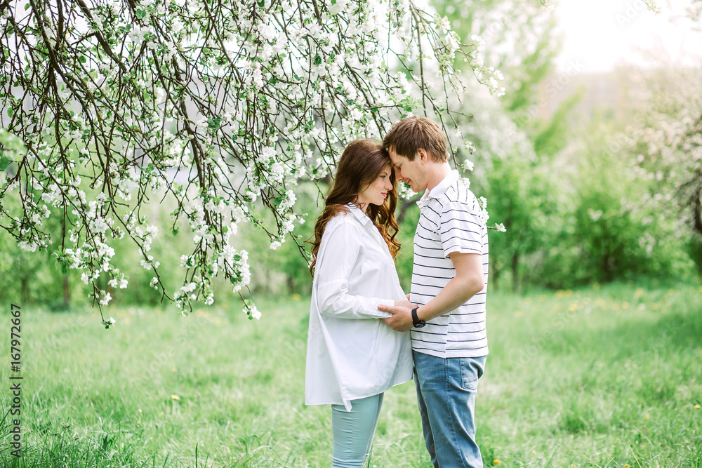 Fototapeta premium Portrait of lovely future parents during sunset on nature apple tree background