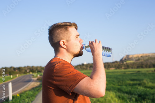 Caucasian man drinking water with his eyes closed after exercises