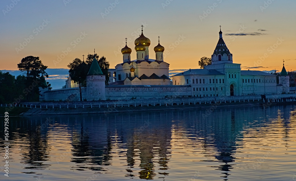 Monastery in the rays of sunset/Ipatievsky Monastery in Kostroma. The domes are illuminated with searchlights.The monastery is on the river bank and is reflected in the river.Golden Ring of Russia