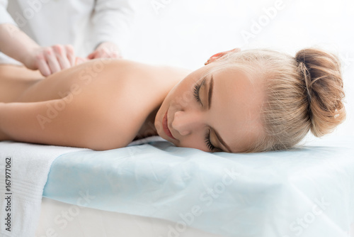 Pretty girl on couch having massage in spa saloon