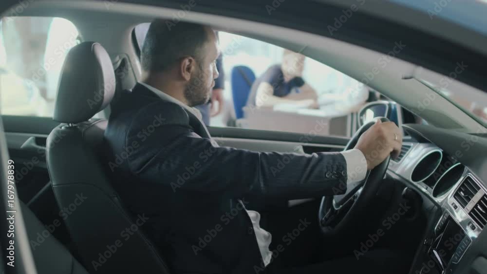 The businessman gets a car's keys from salesman on gyroscope in car dealership The businessman gets a car's keys from salesman on gyroscope in car dealership