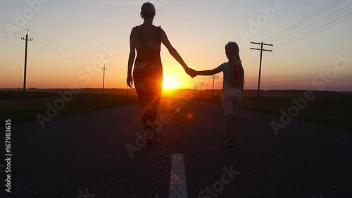 Family walking on the evening road during sunset. Child with mom. photo
