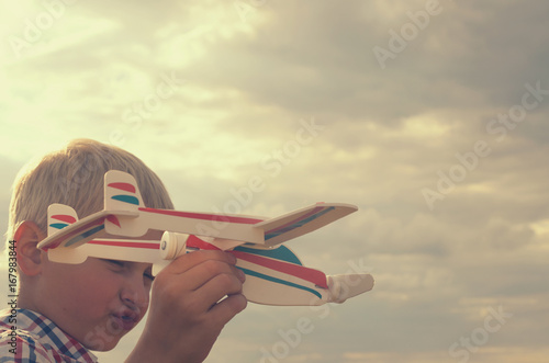 The boy with his hand runs the model of the plane into the sky.