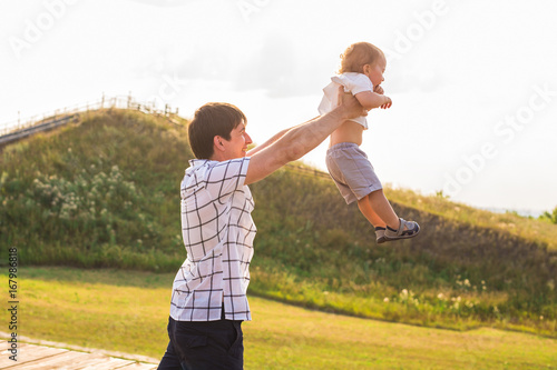 Happy young father and son playing together and having fun in the summer or autumn field. Family, child, fatherhood and nature concept