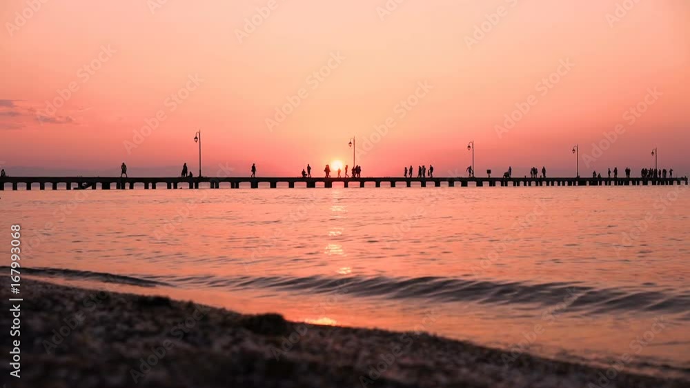 Sea and Sunset at old Jetty with people silhouettes walking and fishing Sea and Sunset at old Jetty with people silhouettes walking and fishing