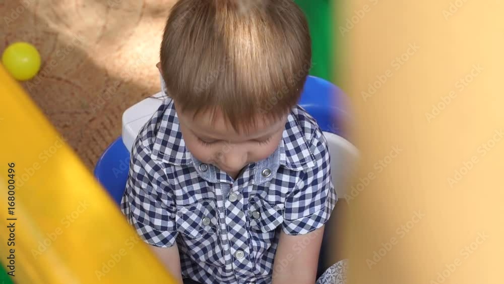 Sad little boy sitting on the Playground. Portrait of a sad child on the Playground. Sad little boy sitting on the Playground. Portrait of a sad child on the Playground.