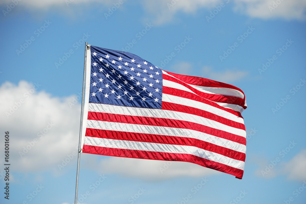 waving USA flag on pole against blue sky