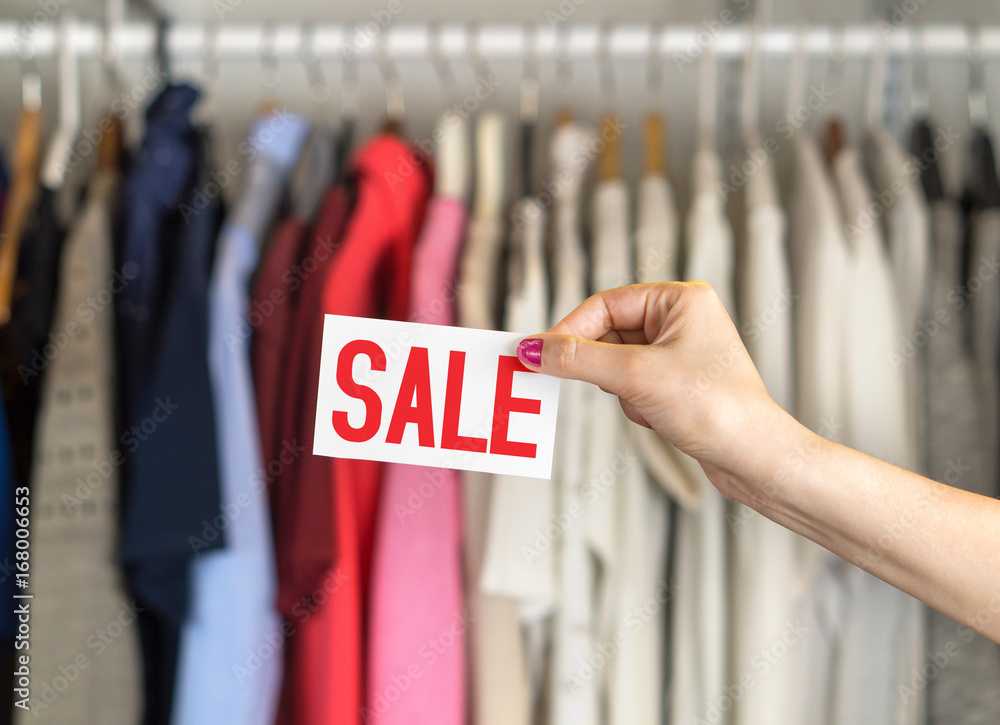 Sale in clothing shop. Clothes hanging in hanger in a rack and wardrobe in a fashion