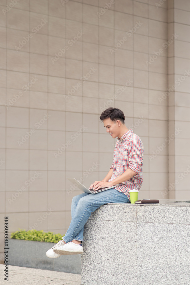 Young man sitting with laptop outside the office Young man sitting with laptop outside the office
