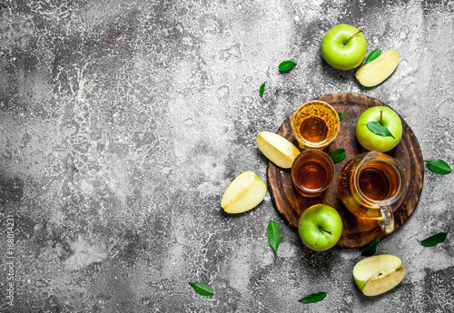 Apple juice in pitcher on the Board with a fresh , green apples.