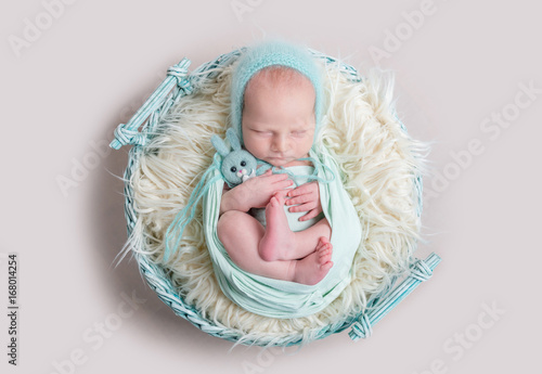 sweet newborn wrapped in a nappy sleeping on a round rug
