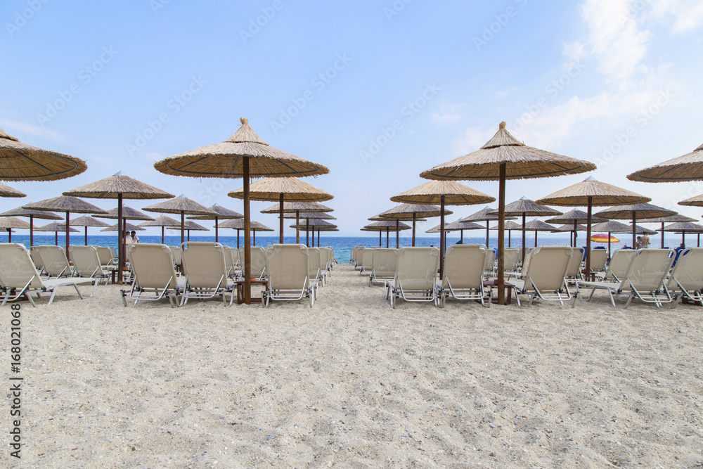 Sun umbrella and beach beds on tropical coastline