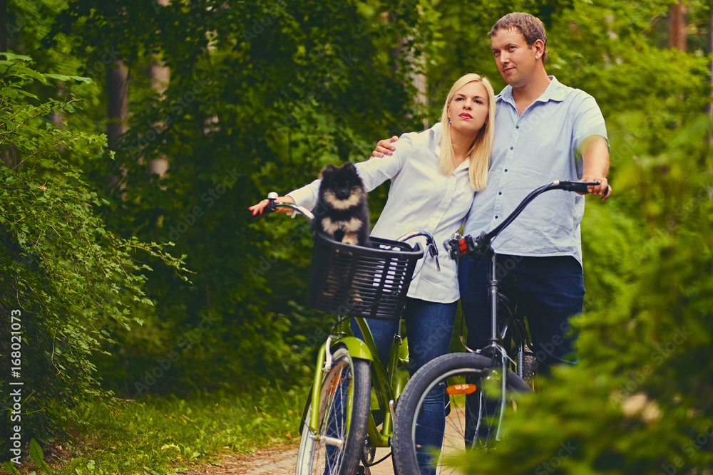 Blond woman and a man on a bicycle ride in a park.