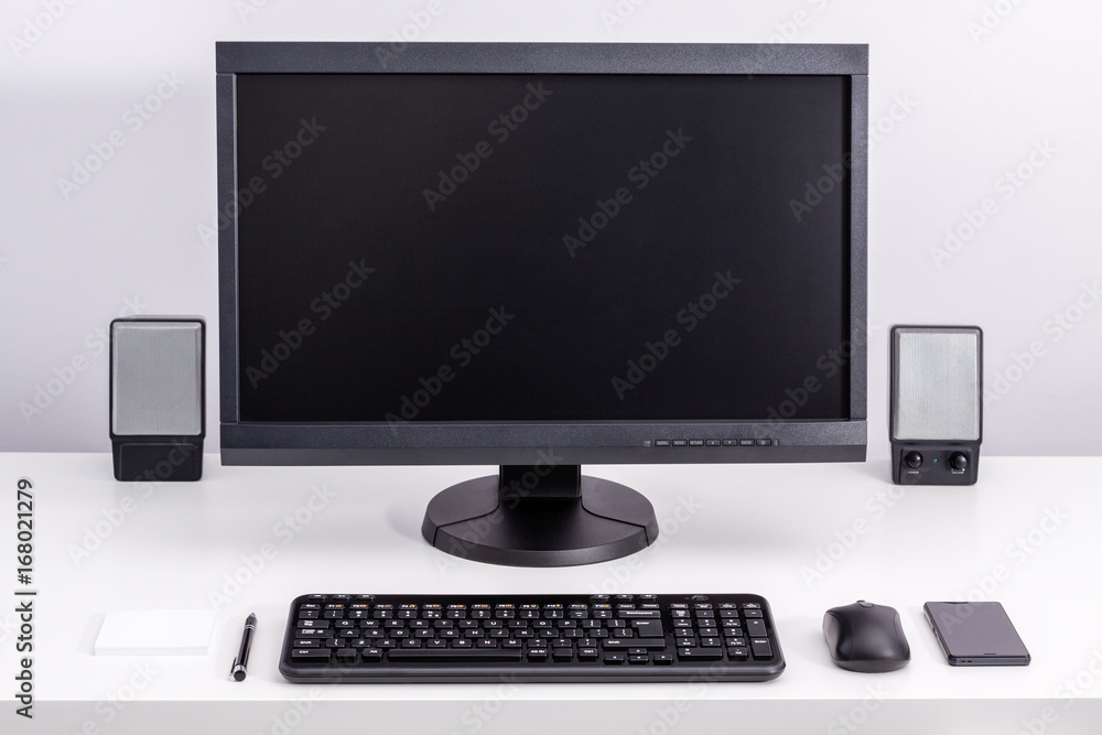 Black blank pc monitor stay on desk, around ordered space to work with keyboard, computer mouse, smartphone, speakers, pen and sticky notes. Black blank pc monitor stay on desk, around ordered space to work with keyboard, computer mouse, smartphone, speakers, pen and sticky notes.