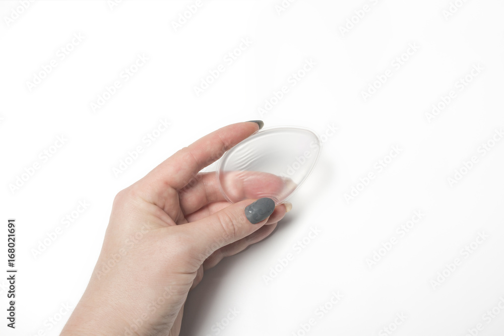 Woman hand holding transparent silicone foundation sponge over a white background Woman hand holding transparent silicone foundation sponge over a white background