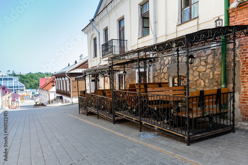 Empty benches and tables of a street bar are waiting for visitors in the morning hours in an empty old town