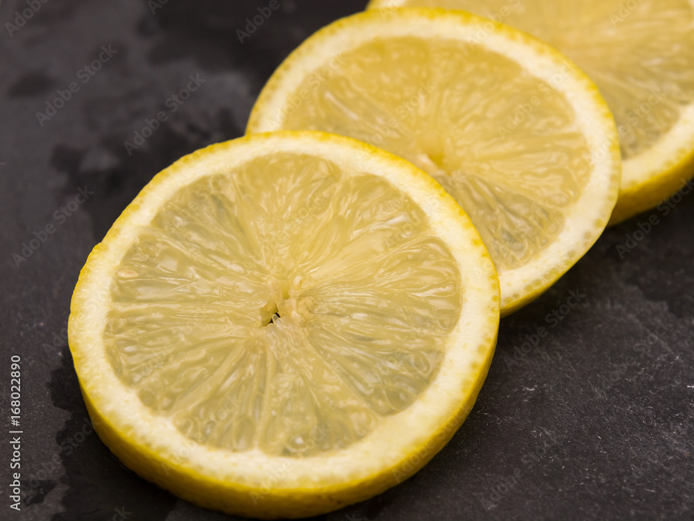 three slices of lemon on slate wet stone