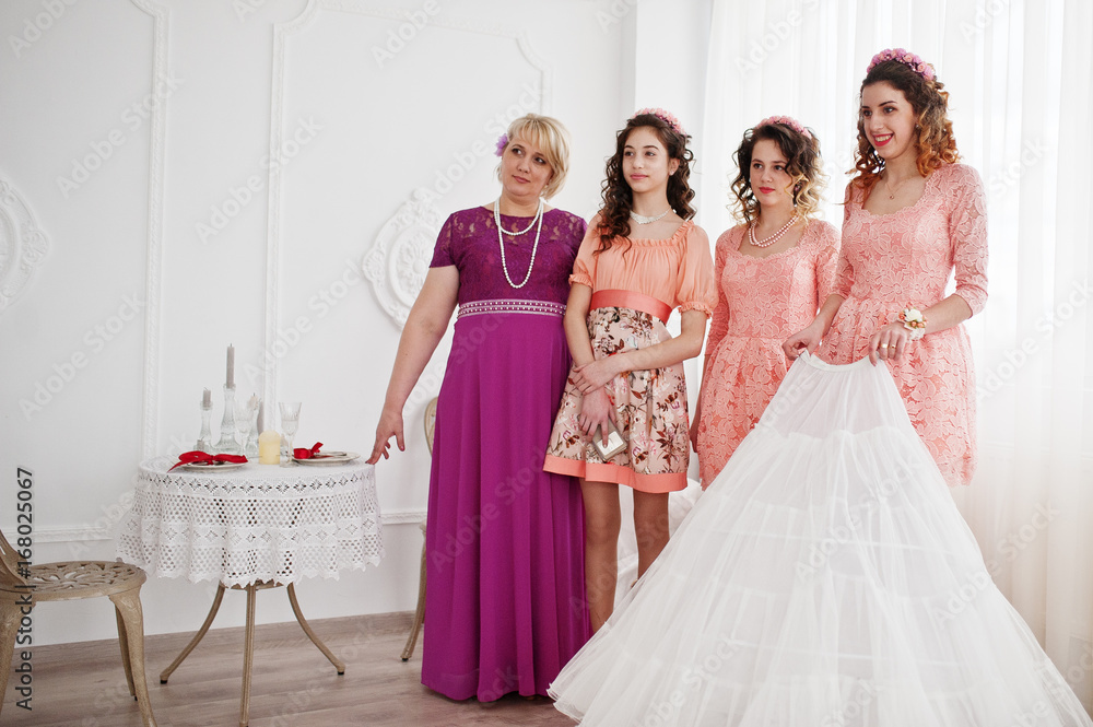 Fototapeta premium Bridesmaids and mother looking at bride while she is dressing up.