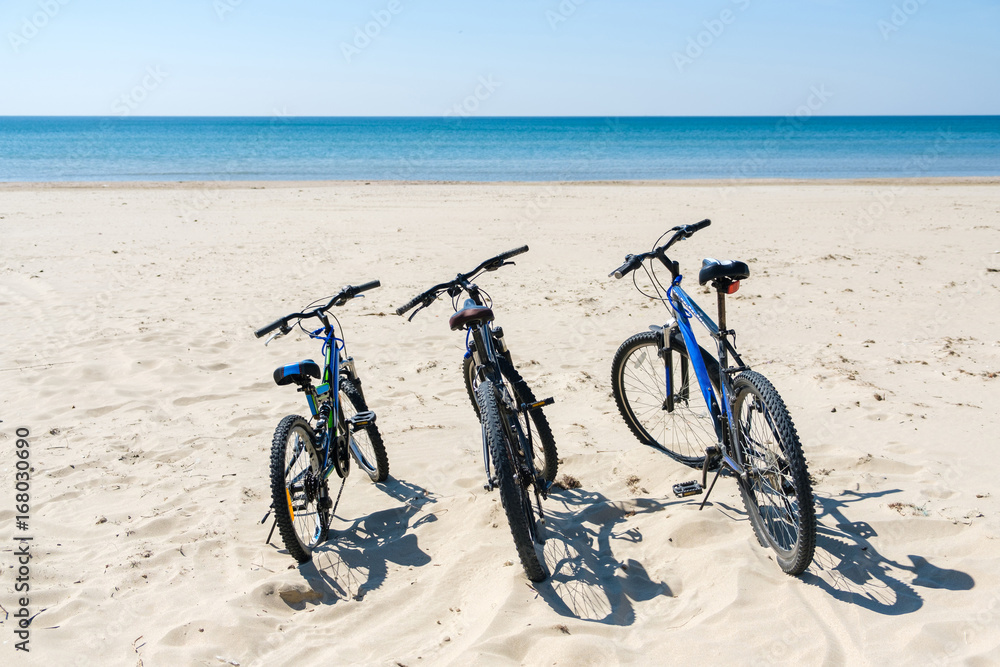 Fototapeta premium Three bicycles are on the beach on sea background