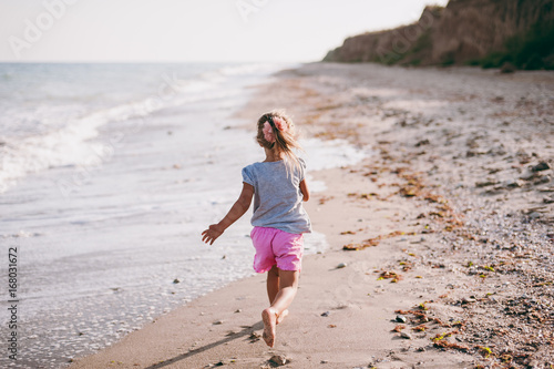 Little girl runs along the beach of the sea