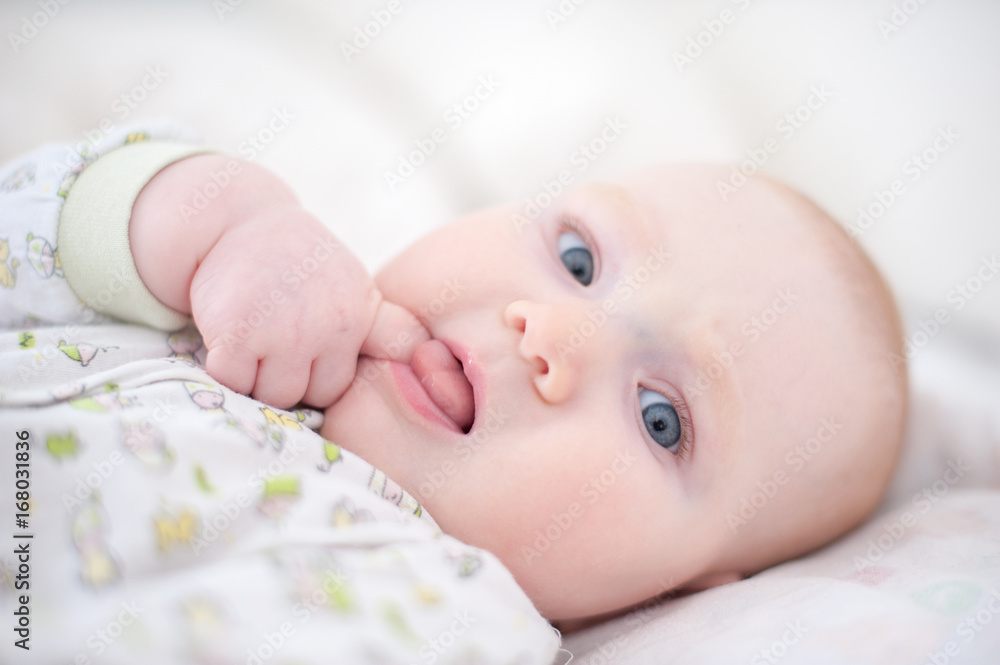 A baby sucking a finger with his tongue out A baby sucking a finger with his tongue out