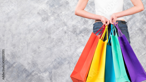 Colourful shopping bags and woman hand on copy space background