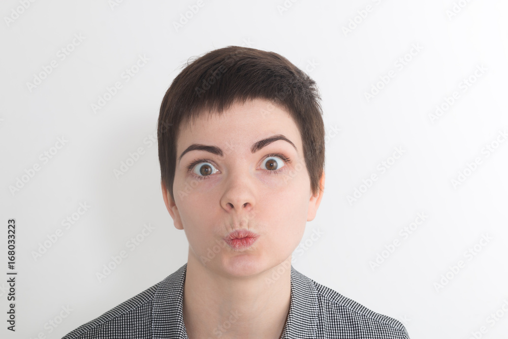 A pretty young woman looks at the viewer with perched lips blowing air or a kiss at the camera A pretty young woman looks at the viewer with perched lips blowing air or a kiss at the camera