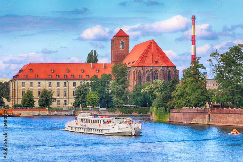Naklejka premium WROCLAW, POLAND - AUGUST 14, 2017: Wroclaw Old Town. Cathedral Island (Ostrow Tumski) is the oldest part of the city. Odra River, boats and historic buildings on a summer day.