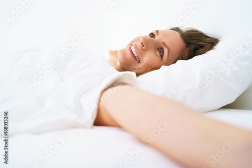 Cute girl sleeping in bed waking up stretching and smiling