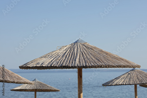 Fototapeta Naklejka Na Ścianę i Meble -  Straw Beach Umbrella and boat against blue sea,ocean. Summer, holiday, vacation background