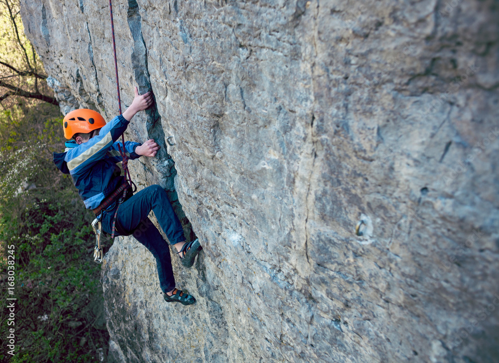 Fototapeta premium Kid rock climber climbs the cliff.