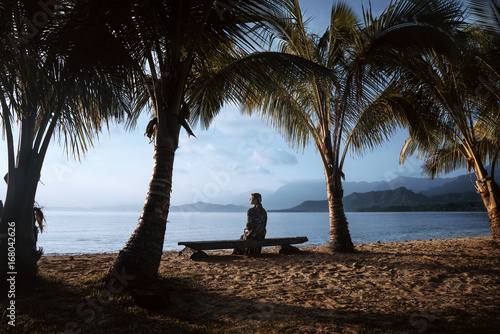 palmtrees at the beach with girl on a bench