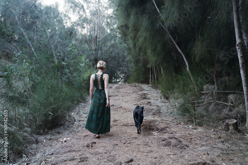 woman with dog walking a forest path