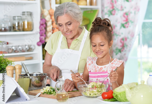 grandmother and granddaughter preparing dinner 