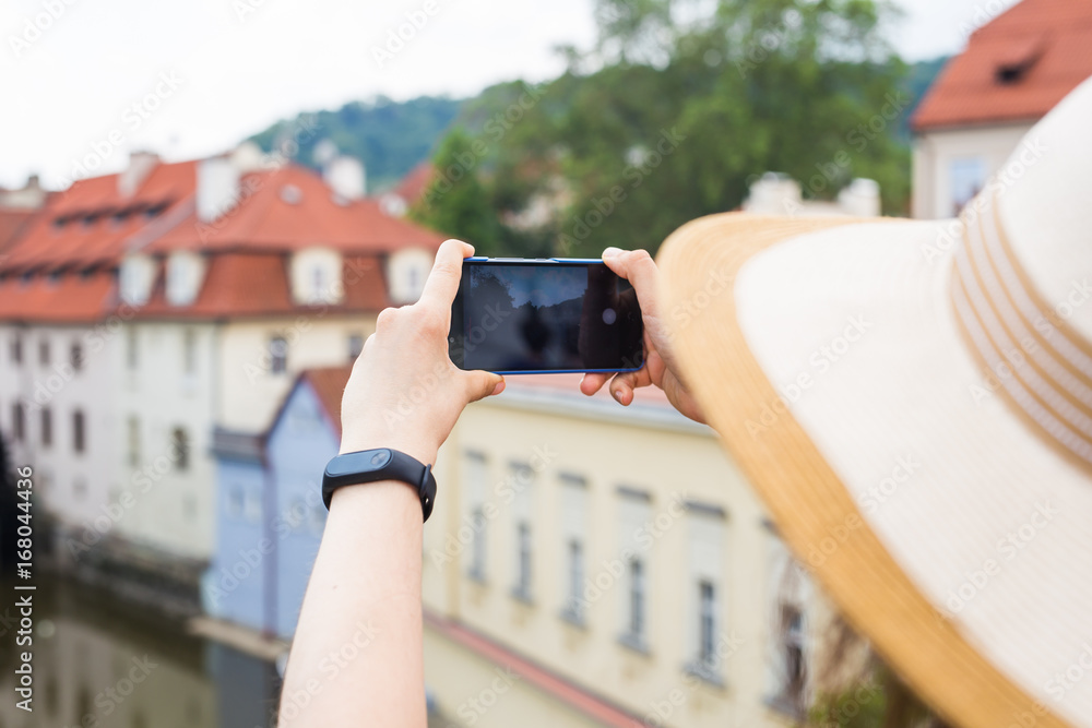 Naklejka premium woman taking picture of Old Town in Prague with a smartphone.