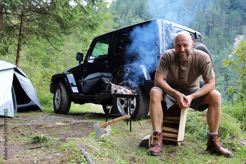 Cuadro en lienzo Mann grillt am Camping Platz vor SUV