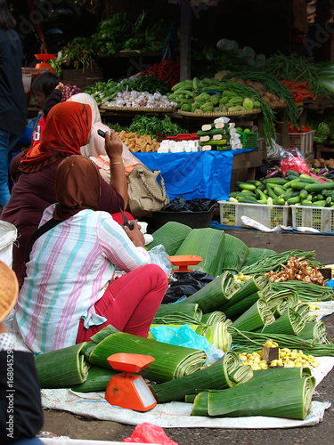 The Sumatran market with muslim women selling banana leaves, vegetables and fruits