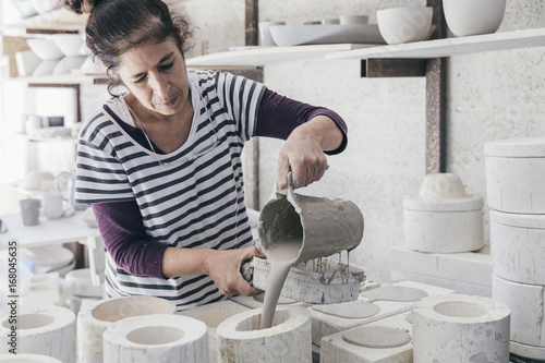 Female ceramic artist pouring slip into a mould