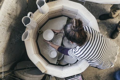 Woman taking ceramic bowls out of kiln