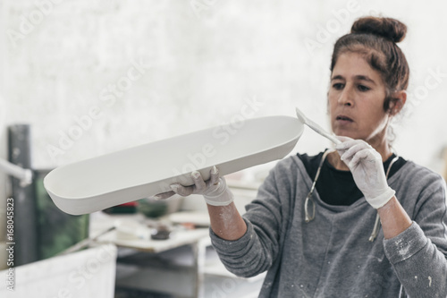 Female ceramic artist painting a hand made bowl